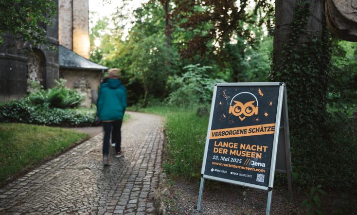 Ein Kind läuft an einem Aufsteller mit Plakat zur Museumsnacht vorbei