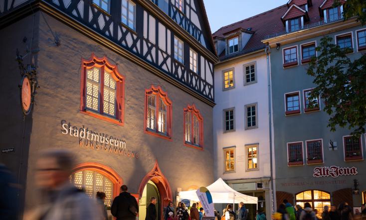 Blick auf das Stadtmuseum Jena bei Nacht mit Besuchern